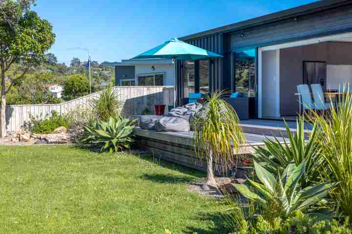 Front deck and dining area at Piritahi Beach House by Waiheke Unlimited