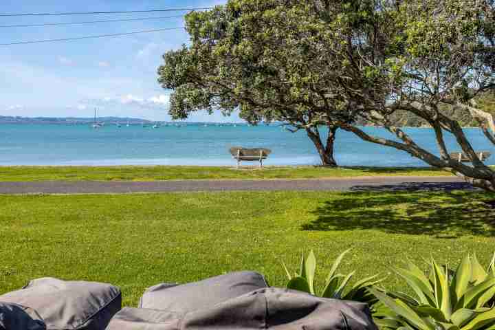 Front lawn from the deck at Piritahi Beach House by Waiheke Unlimited