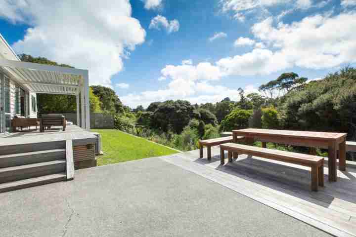 Large deck, lawn, outdoor dining and private spa pool at Waiheke family home