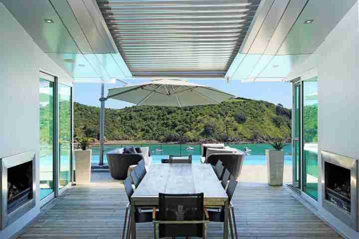Outdoor entertainment area with modern seating, fireplace, pool and sea views