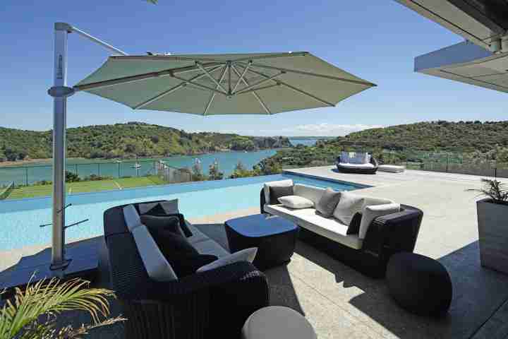 Outdoor seating at Korora Estate, with views of tennis court, garden and sea
