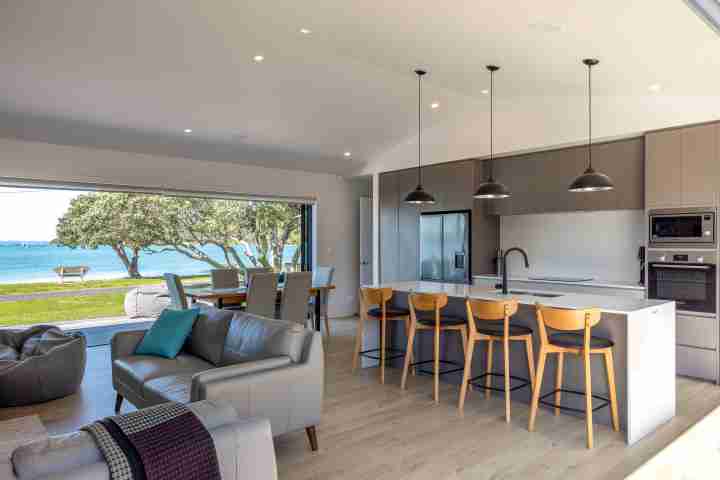 Open plan living and dining at Piritahi Beach House by Waiheke Unlimited