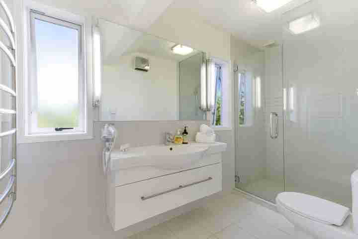 Clean modern bathroom with large shower and view of toilet and sink