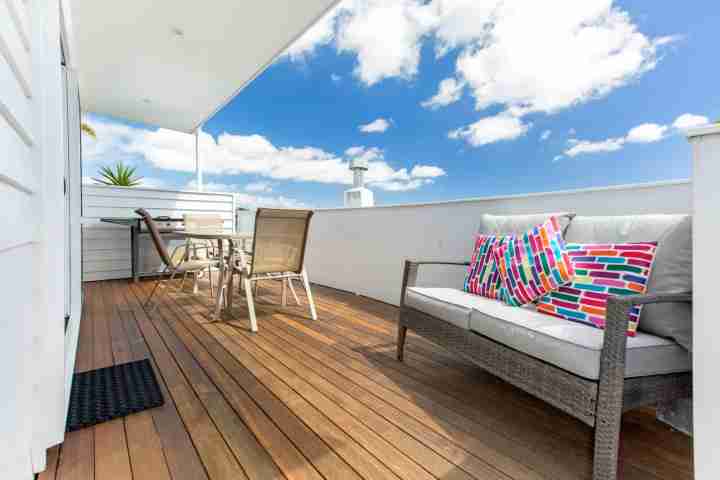 Sunny outdoor deck with outdoor furniture and BBQ in comfortable Waiheke Apartment