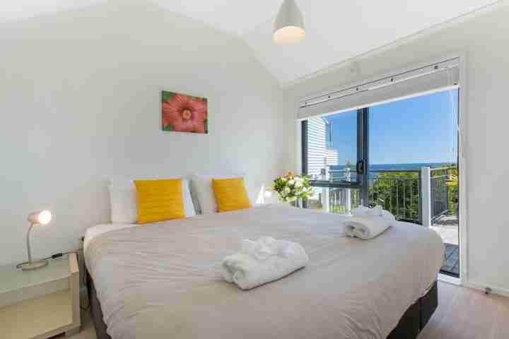 Large double bed with deck access and sea view at The Resort, Waiheke